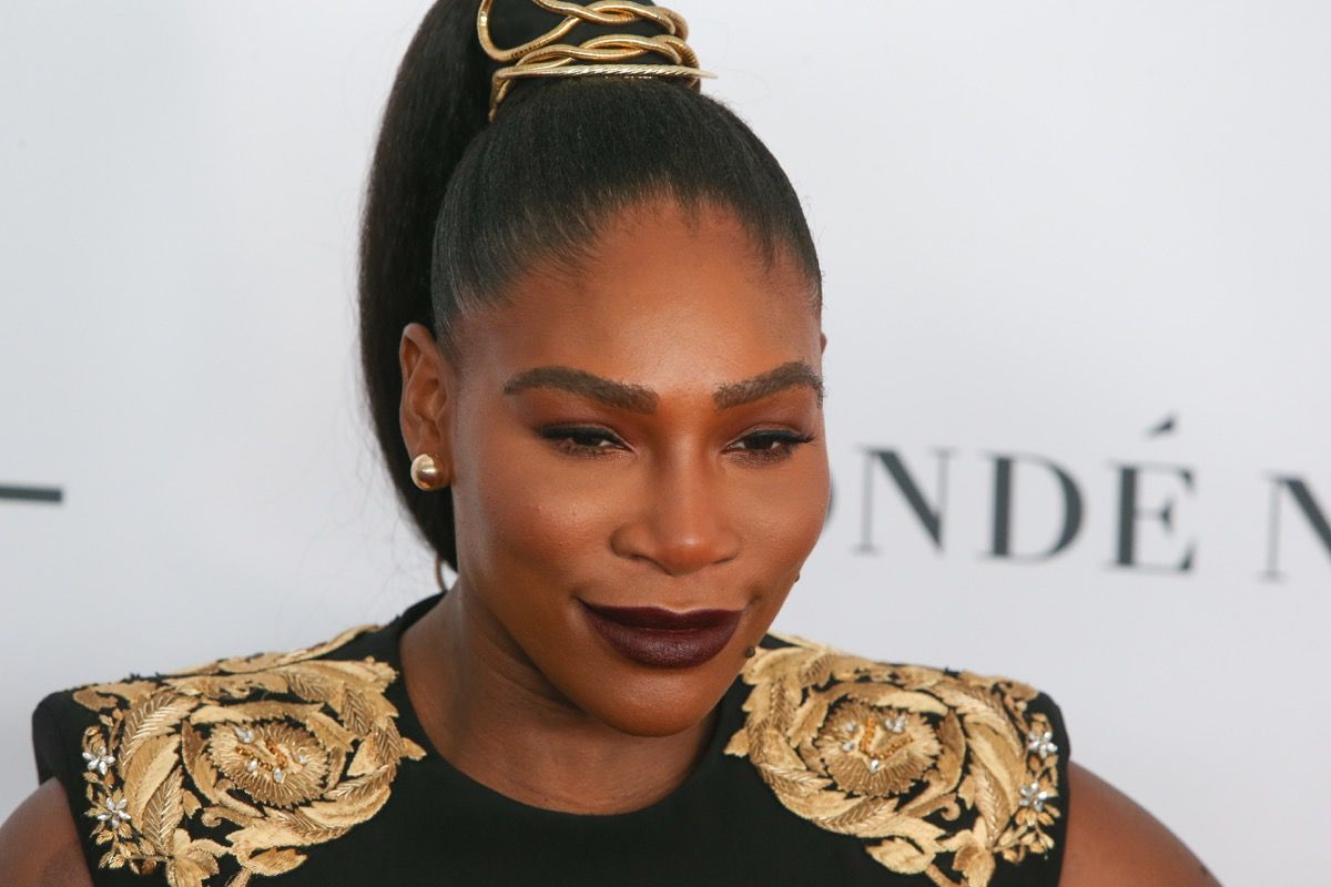 Serena Williams ant raudono kilimo juodos ir auksinės spalvos aprangoje
