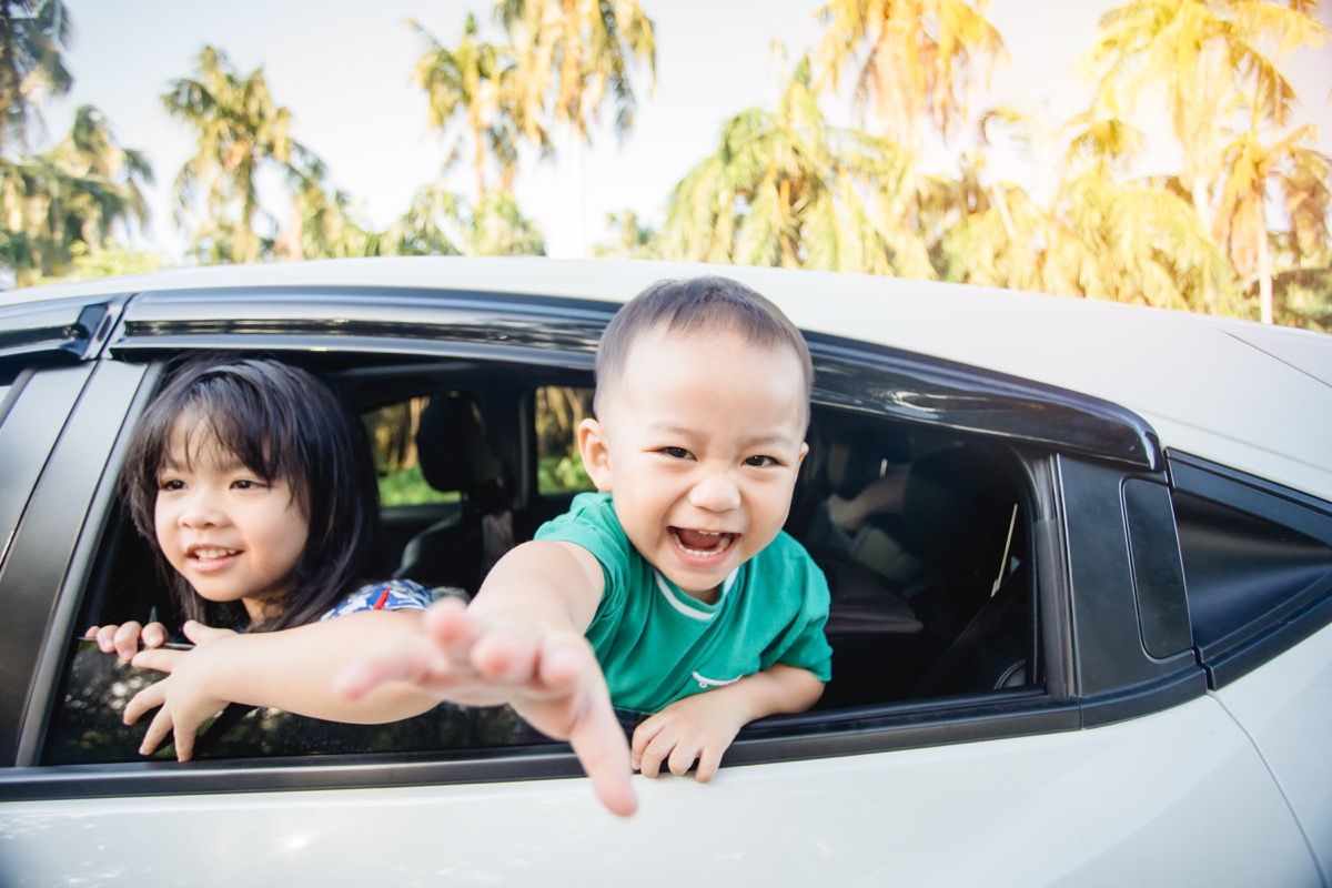 Les enfants asiatiques rient sur la banquette arrière de la voiture
