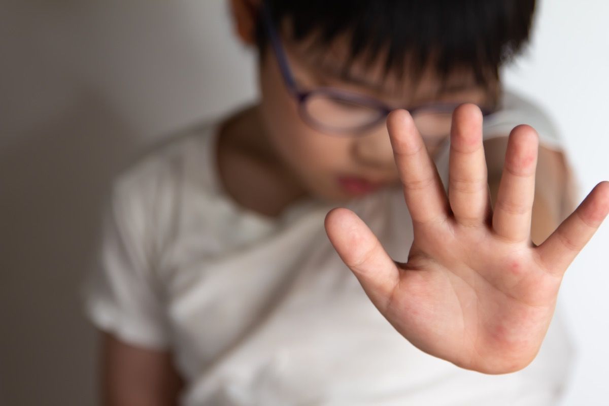 Aziatische jongen steekt zijn hand op om te voorkomen dat hij wordt geslagen