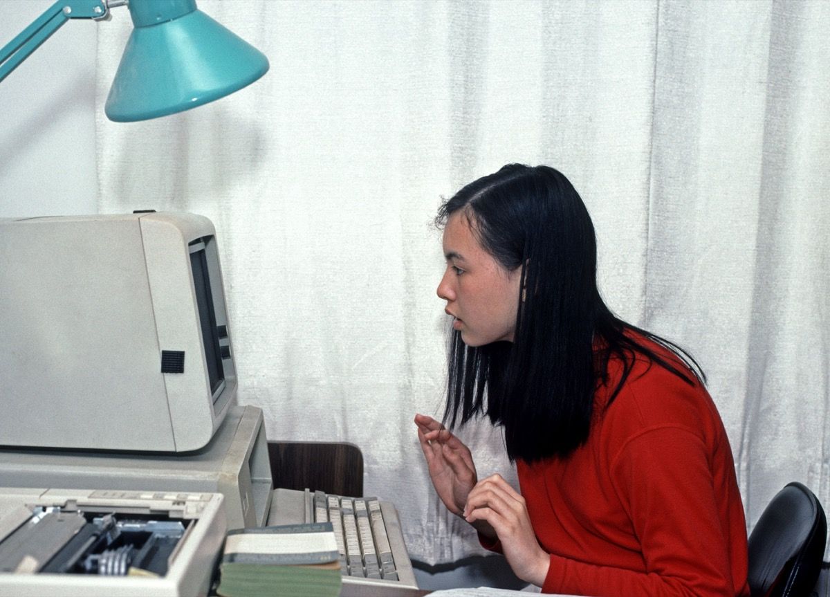 Gadis Asia menggunakan komputer rumah PC pada tahun 1990-an