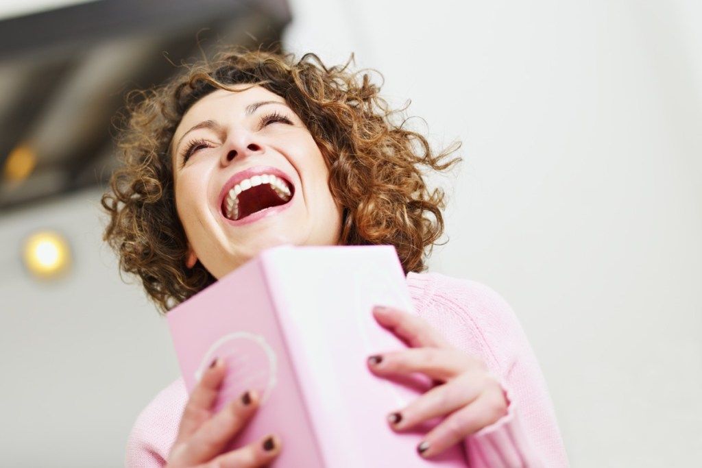 nainen nauraa lukiessaan kirjaa - hauskoja kirjoja