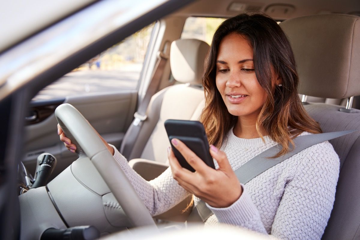 млада жена, която гледа телефона си в колата