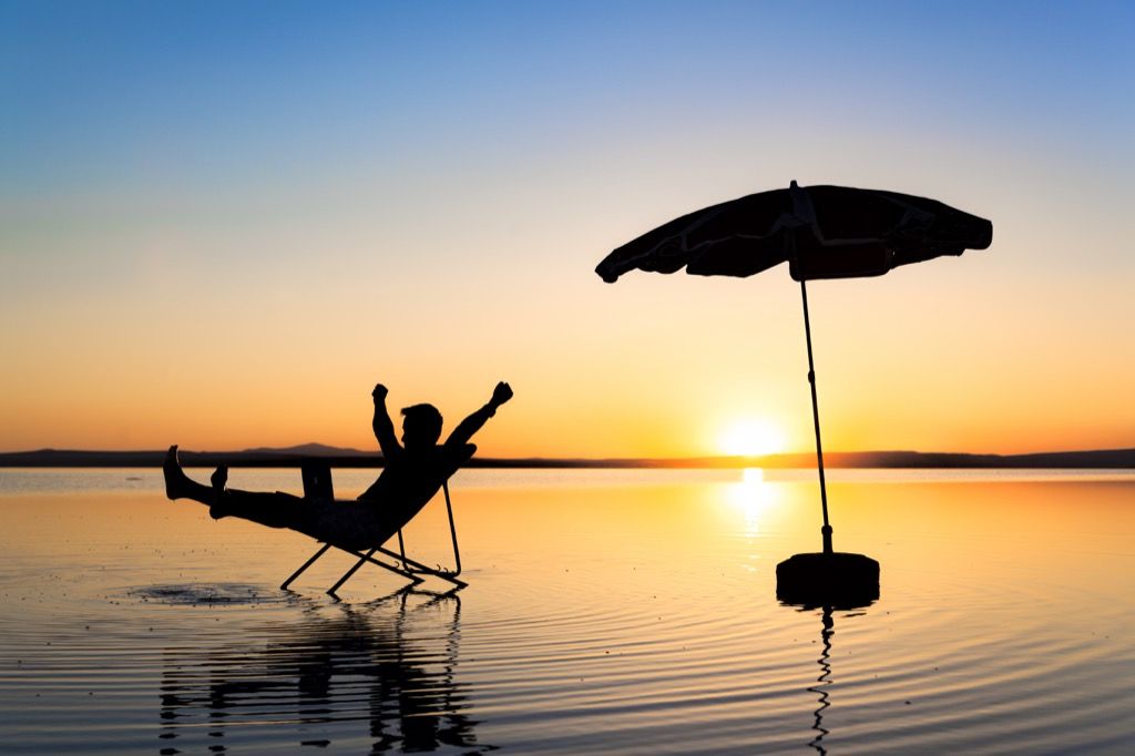 Hombre relajándose en la playa al atardecer en una silla - chistes más divertidos