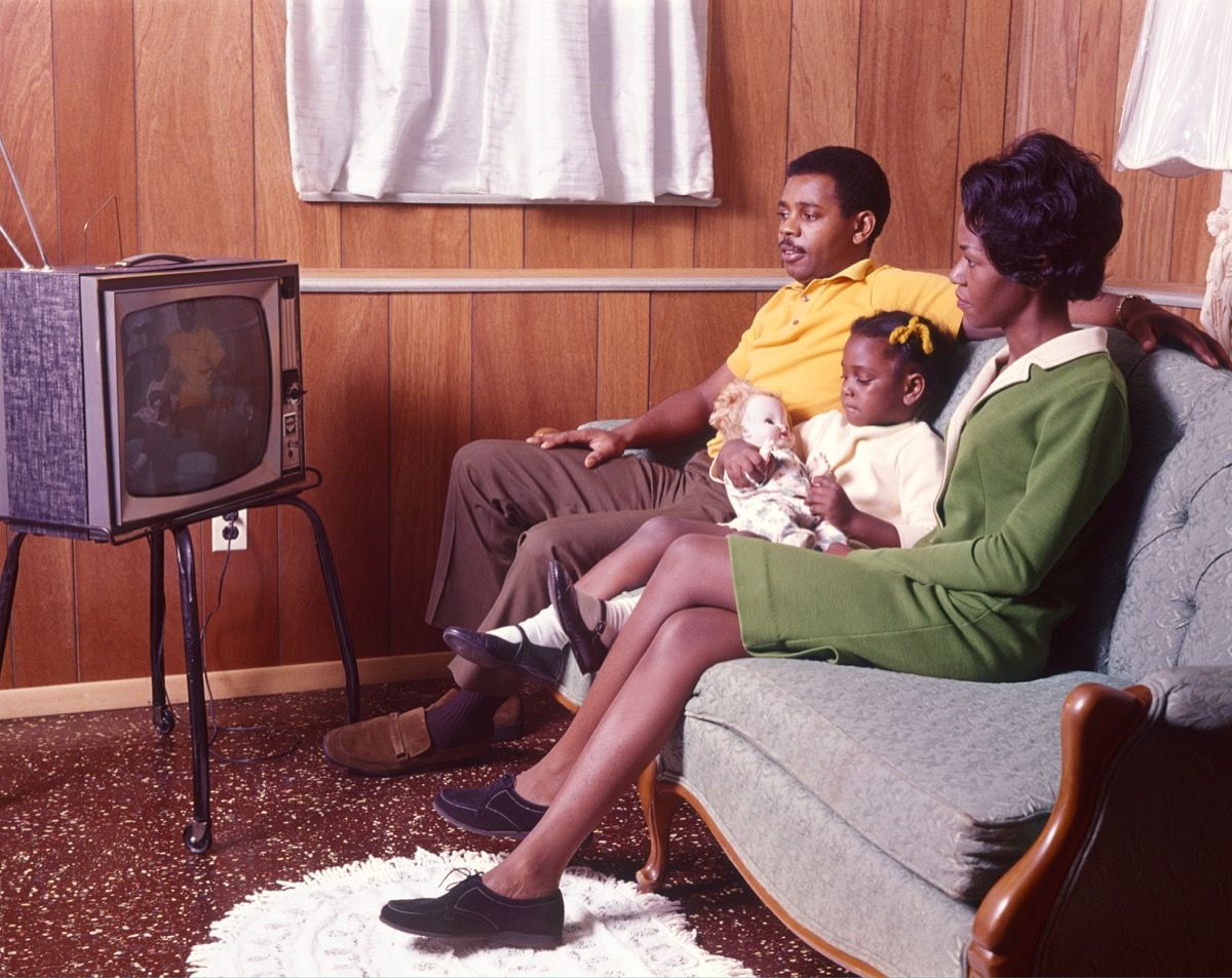Crna obitelj iz 1970-ih, mama i tata i kćer, gledaju TV