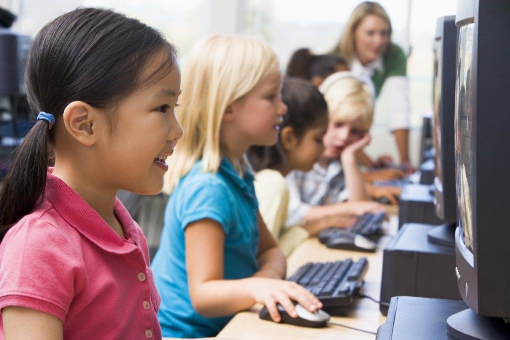 basisschoolkinderen in een computerlokaal met oude technologie
