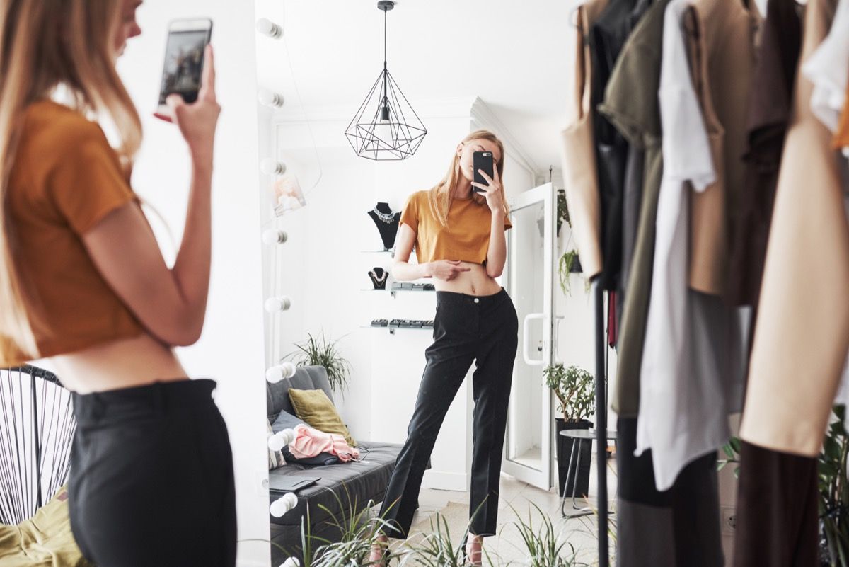 moteris influencerė, fotografuodama savo aprangą viso ilgio veidrodyje