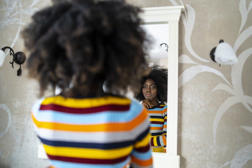 juodaodė moteris, žiūrinti į veidrodį