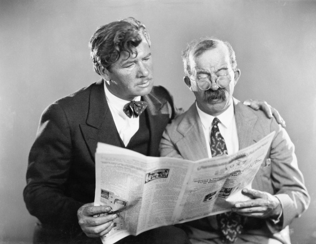 Tappning-se foto av två män som läser en tidning