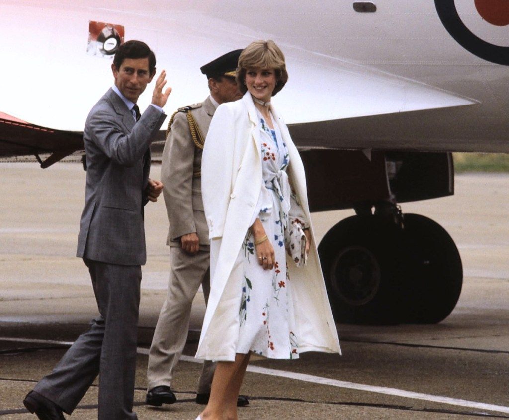 Księżna Diana ubrana w biały płaszcz, gdy wsiada do samolotu z księciem Karolem 1981