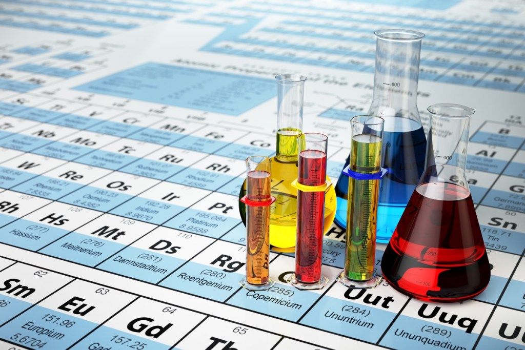 مفهوم علم الكيمياء. أنابيب وقوارير اختبار معملية تحتوي على سوائل ملونة في الجدول الدوري للعناصر ، حقائق أكثر ذكاءً