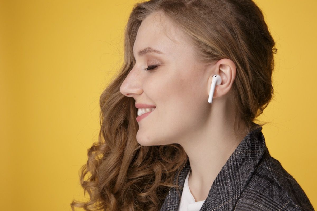 tânără albă arătată din profil cu airpod-uri, căști fără fir, în urechi