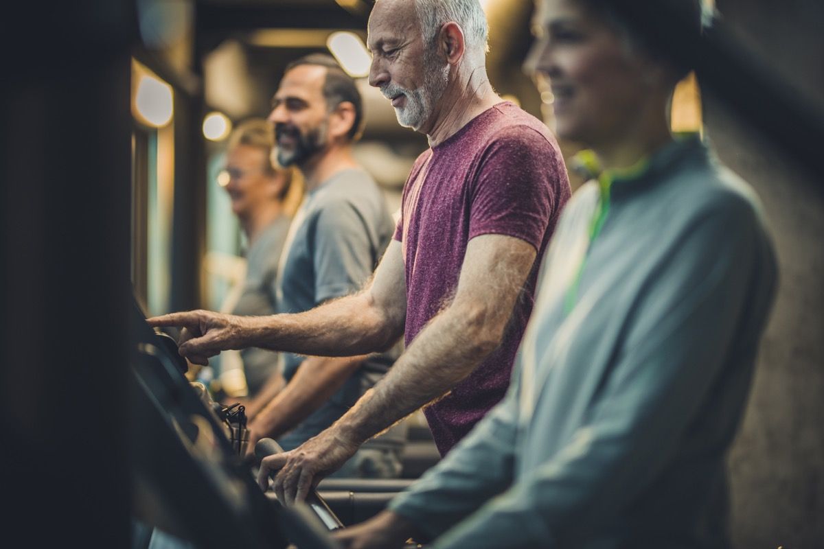 Gruppe von sportlichen Senioren, die auf Laufbändern im Fitnessstudio trainieren