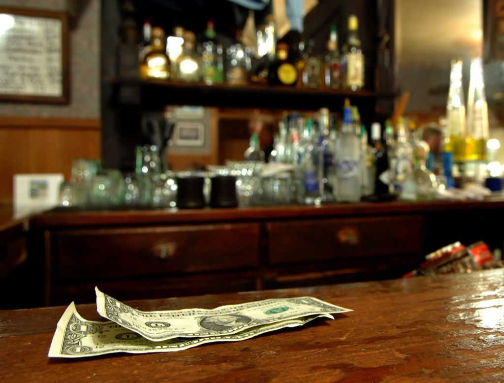 dollarsedler sidder oven på baren som tip til bartender