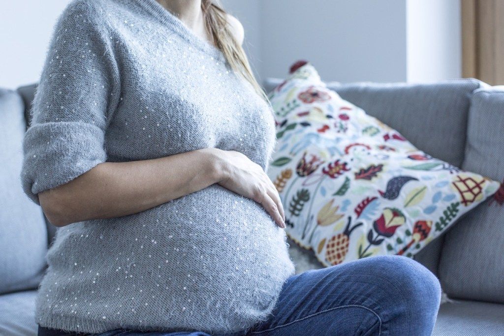 Femeie însărcinată așezată pe o canapea