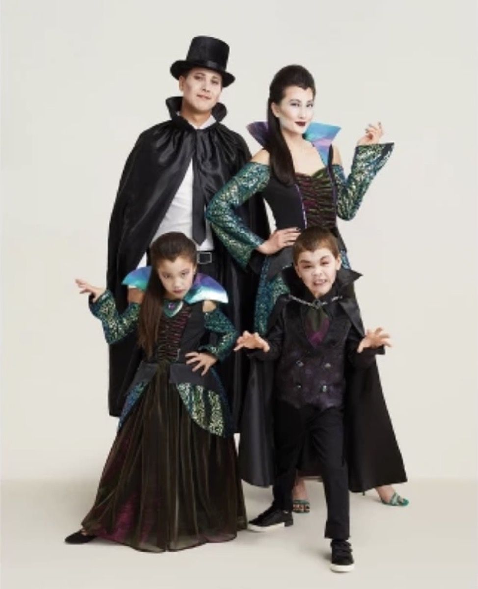 bărbat, femeie și doi copii mici îmbrăcați în vampiri, costume de Halloween de familie