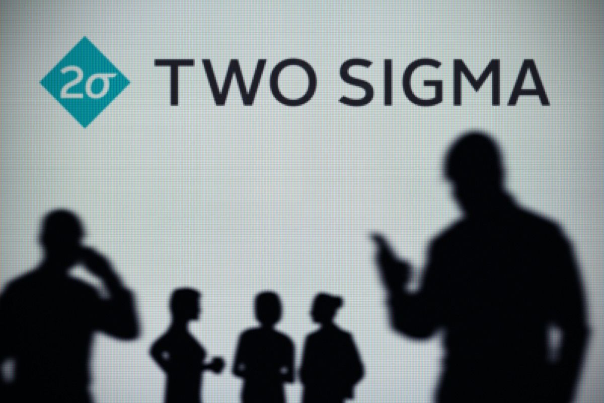 El logotipo de Two Sigma se ve en una pantalla LED en el fondo mientras una persona de la silueta usa un teléfono inteligente
