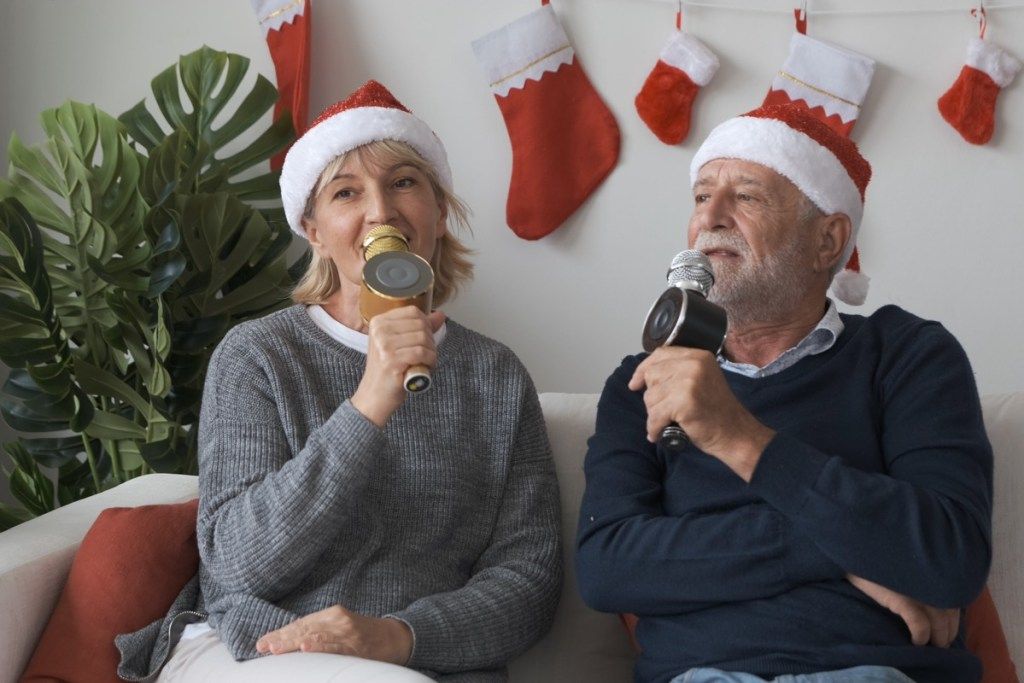 du vyresni žmonės, dainuojantys kalėdinę karaokę
