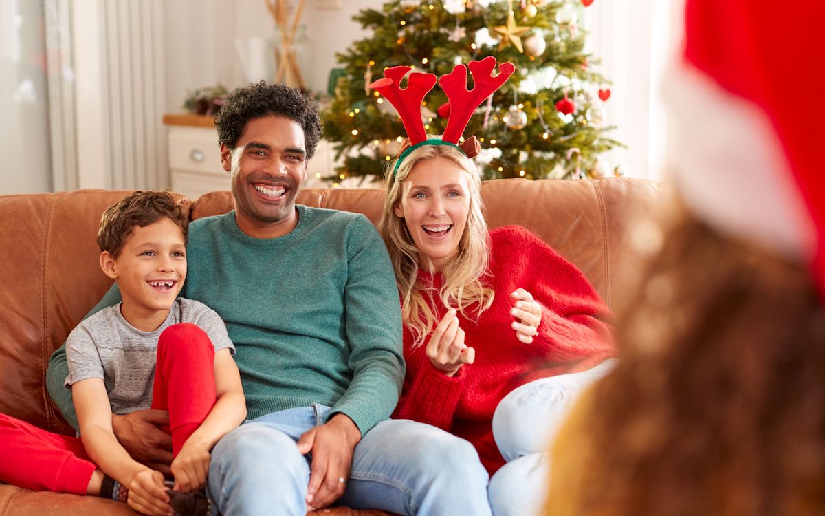Familia sentada en el sofá jugando a juegos de charadas en Navidad juntos