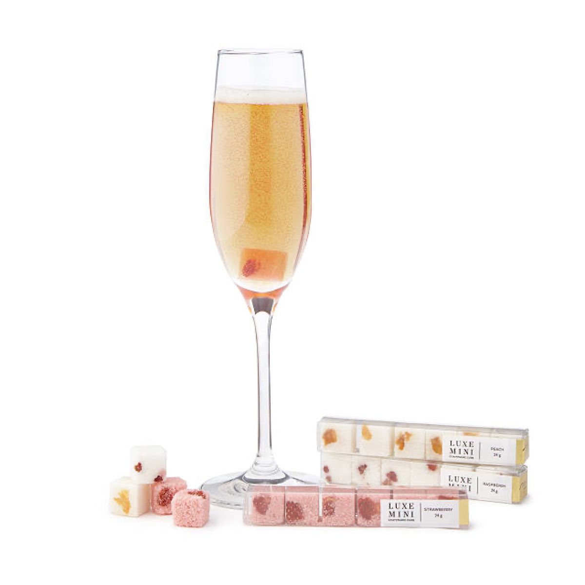 šampanieša glāze blakus rozā cukura kubiņiem
