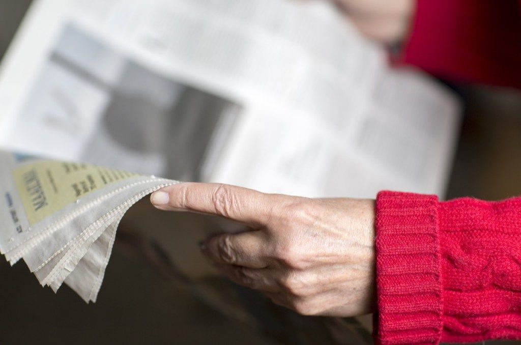 mujer mayor leyendo el periódico, rutas de papel