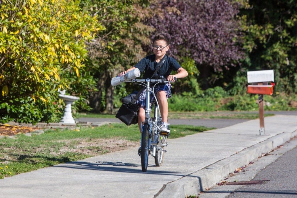 niño llevando periódico en bicicleta, ruta del papel