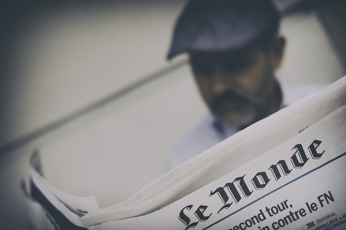 mees loeb ajalehte, mille ülaosas on prantsuse kiri