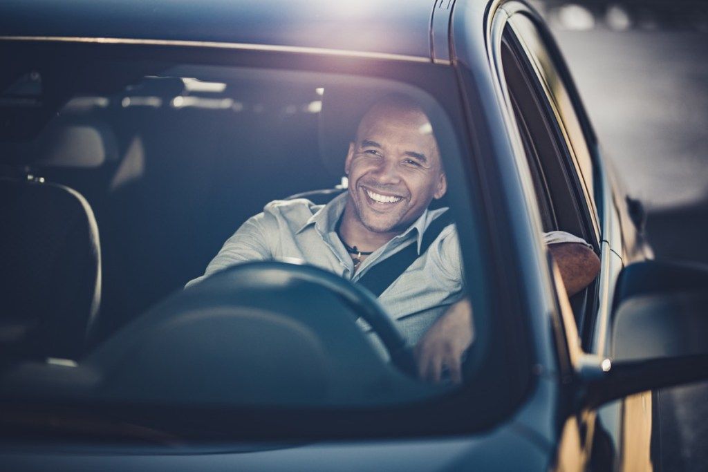 Gelukkig zwarte zakenman genieten tijdens het autorijden.