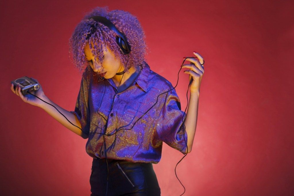 mlada afroameriška ženska z vintage oblačili, ki posluša glasbo s svojim walkmanom - slika