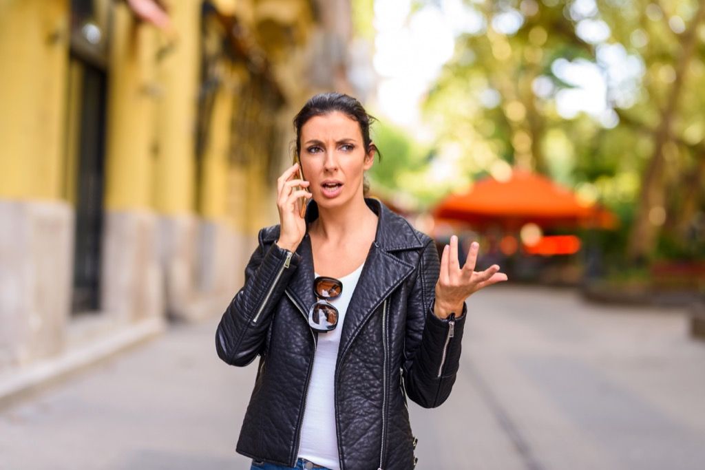 ผู้หญิงบนถนนคุยโทรศัพท์อย่างร้อนรนสิ่งที่ไม่ควรพูดกับตัวแทนฝ่ายบริการลูกค้า