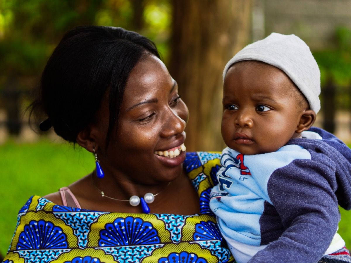 Mujer zimbabuense sonriendo al bebé en sus brazos