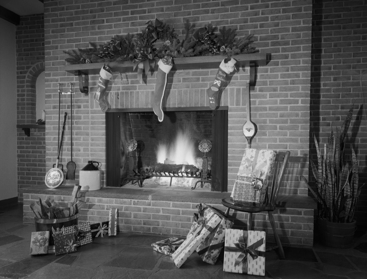 เตาผิงอิฐในรูปถ่ายขาวดำประดับด้วยถุงน่องและของขวัญสำหรับคริสต์มาสในบ้านหลังใหญ่