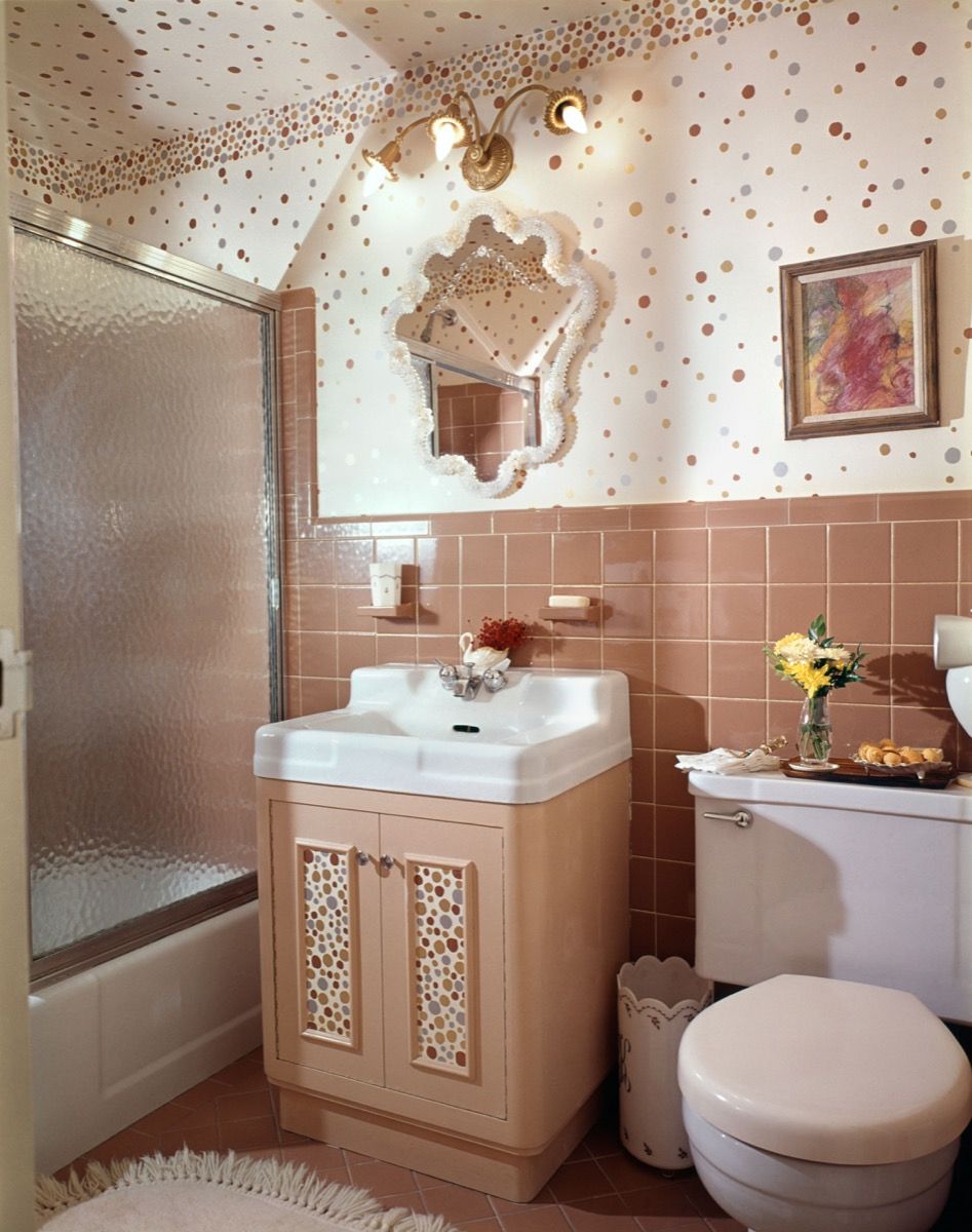 ห้องน้ำขนาดใหญ่ในปี 1960 พร้อมฝักบัวและอ่างอาบน้ำอ่างล้างหน้าเดี่ยวและห้องสุขาประดับด้วยกระเบื้องสีชมพู