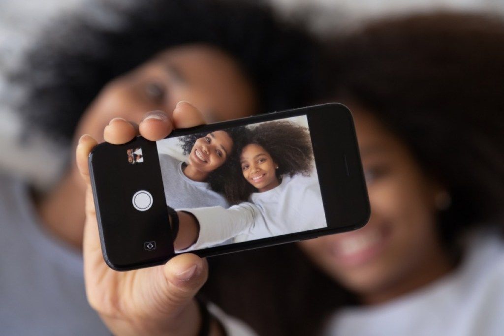 mamá e hija tomando fotos de sí mismas en el teléfono, preparan a los niños para el divorcio