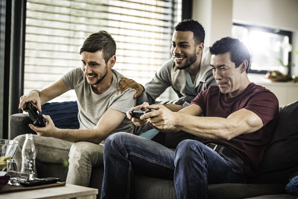 joven blanco hombre negro y hombre asiático jugando videojuegos
