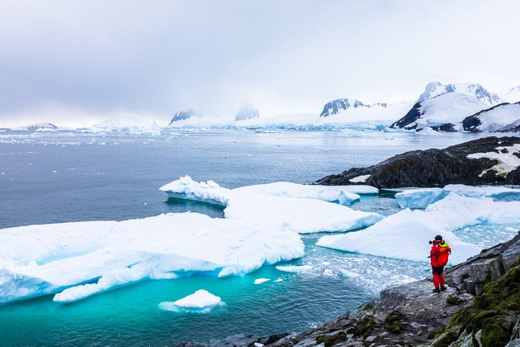 Turista tomando fotos del increíble paisaje helado en la Antártida con icebergs, nieve, montañas y glaciares, hermosa naturaleza en la Península Antártica con hielo (Turista tomando fotos del increíble paisaje helado en la Antártida con icebergs, nieve, mountai