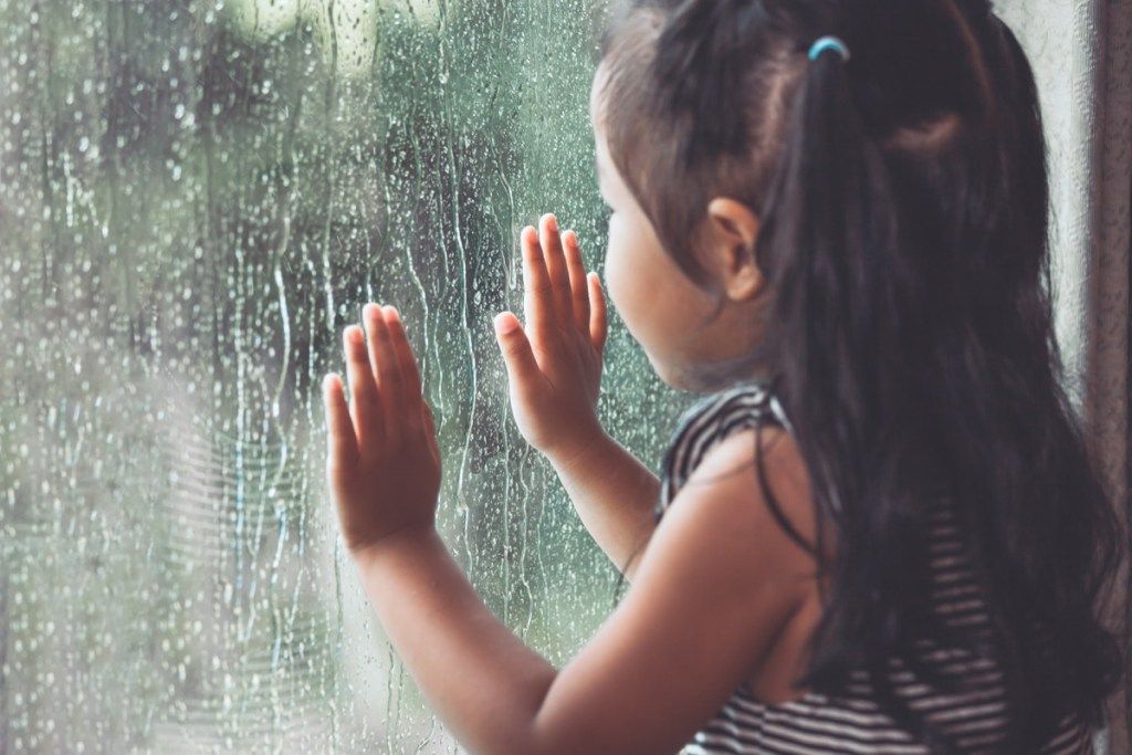 Маленькая девочка смотрит на дождь в окне, слова каждый день