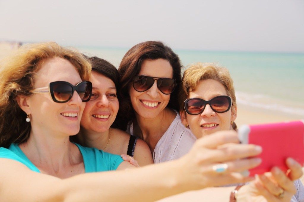 Phụ nữ lớn tuổi cười trên bãi biển khi chụp ảnh tự sướng