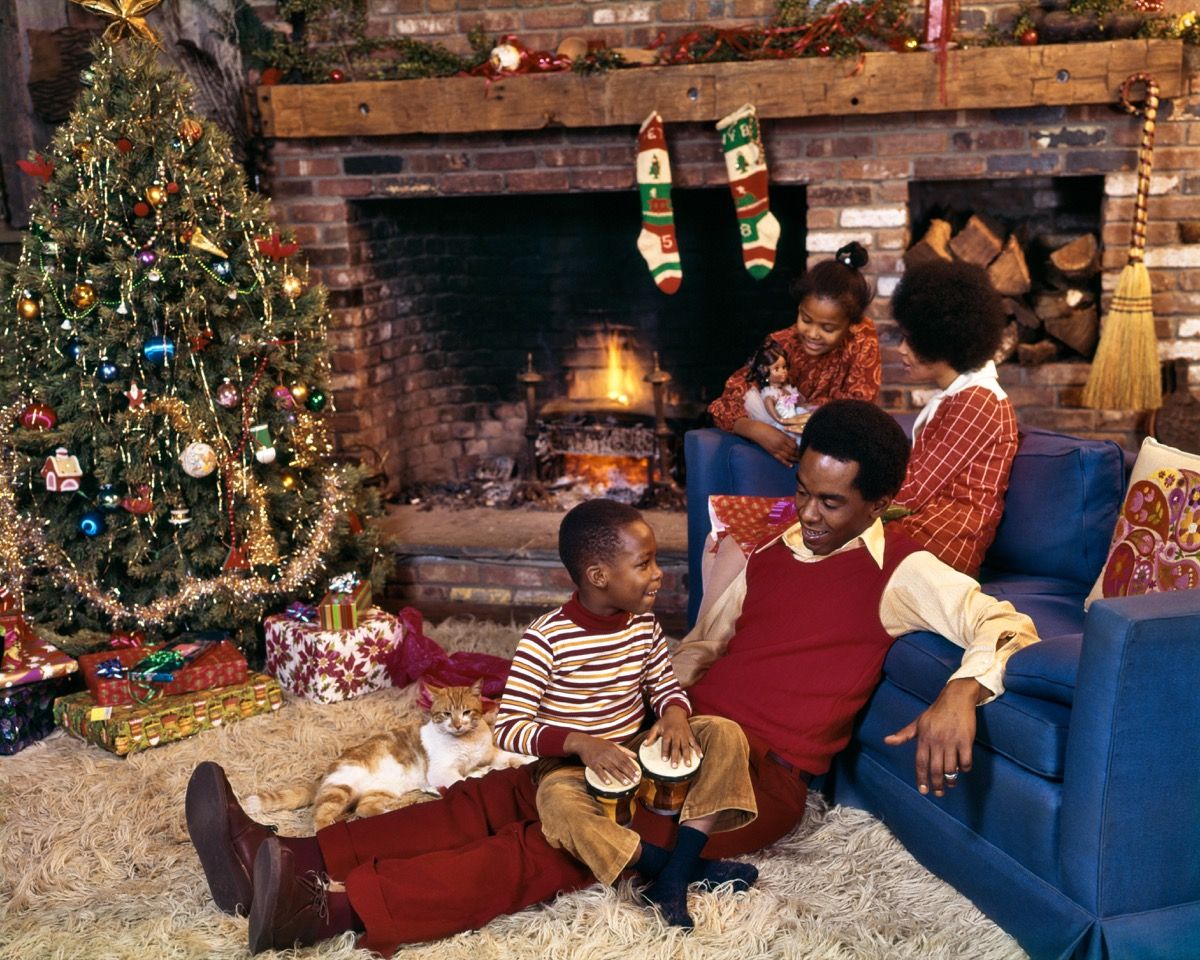 Família negra dos anos 1970 na sala de estar com tapete felpudo no Natal