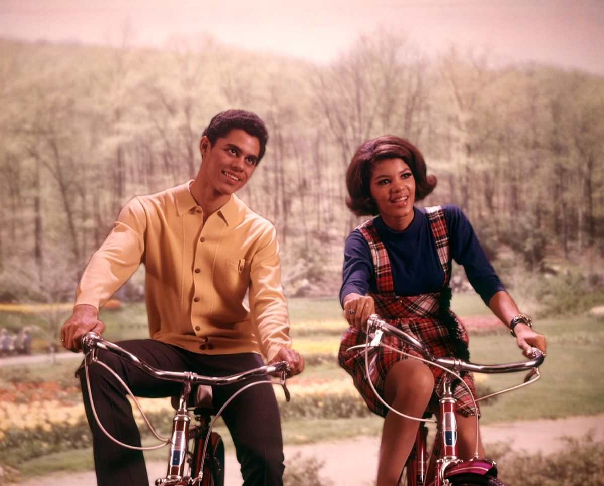 1960. gadu ĀFRIKAS AMERIKAS pusaudžu zēns un meitene brauca ar velosipēdiem