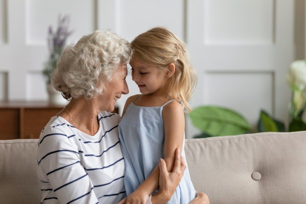 Abuela abrazando a su nieta mientras está sentada en un sofá