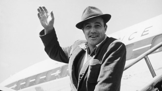   Gene Kelly saludando desde los escalones de un avión alrededor de la década de 1950