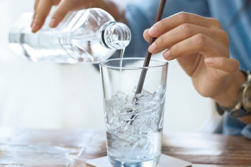  osoba nalievajúca ľadovú vodu do pohára