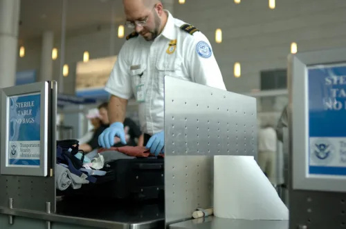   ஒரு TSA முகவர் விமான நிலையத்தில் சாமான்களைத் தேடுகிறார்.