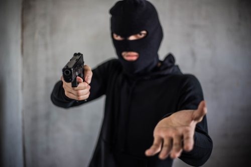   Bandido portando un arma, con una máscara negra.
