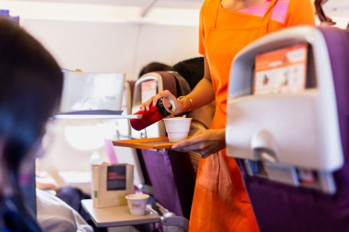  Flygvärdinna som serverar drinkar till passagerare ombord.