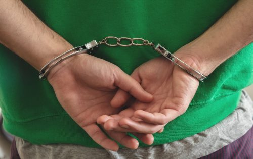  Арест, ръце на престъпник с белезници отблизо
