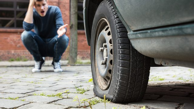 Neumático de un hombre pinchado después de conducir sobre un lingote de plata de 100 onzas