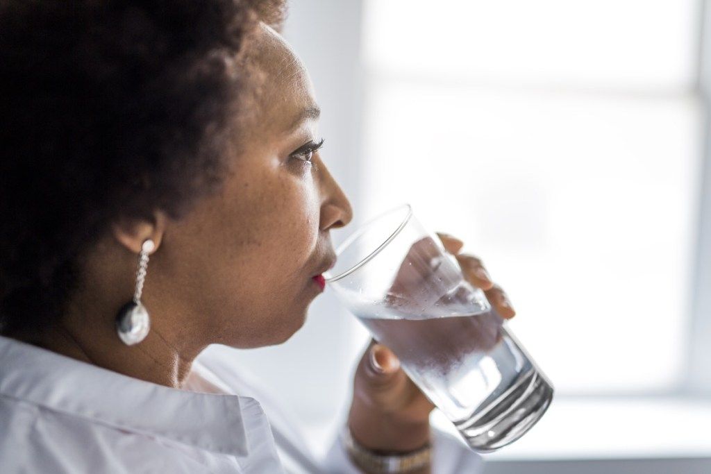 Melnādainā pusmūža sieviete dzer ūdens ieradumus, kas palēnina novecošanos