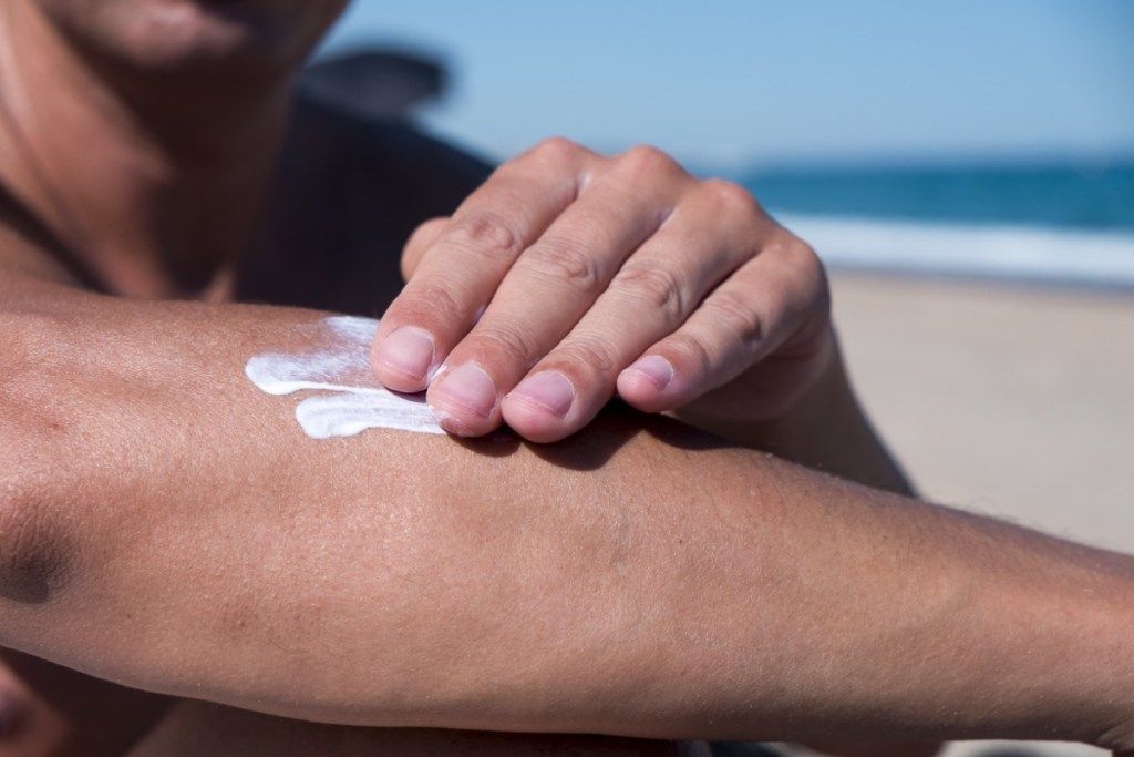 Mann, der Sonnenschutzmittel an einem Strand anwendet