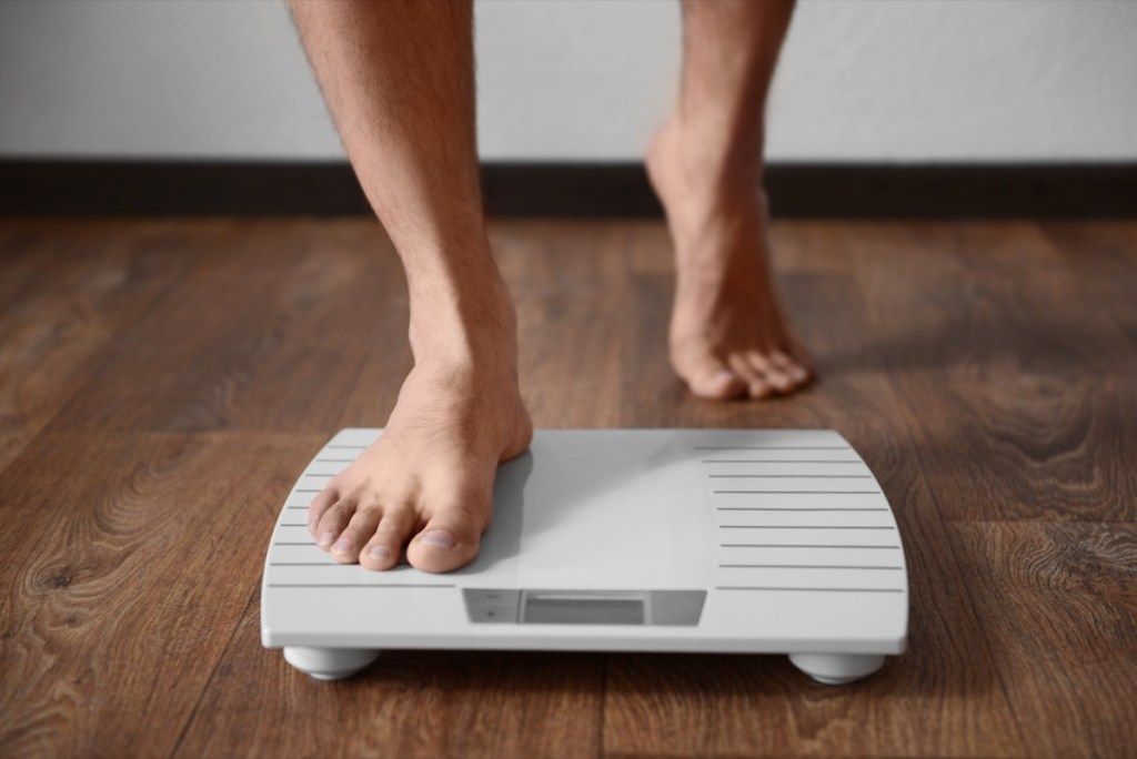 انسان اپنے وزن کو دیکھتے ہوئے پیمانے پر جارہا ہے